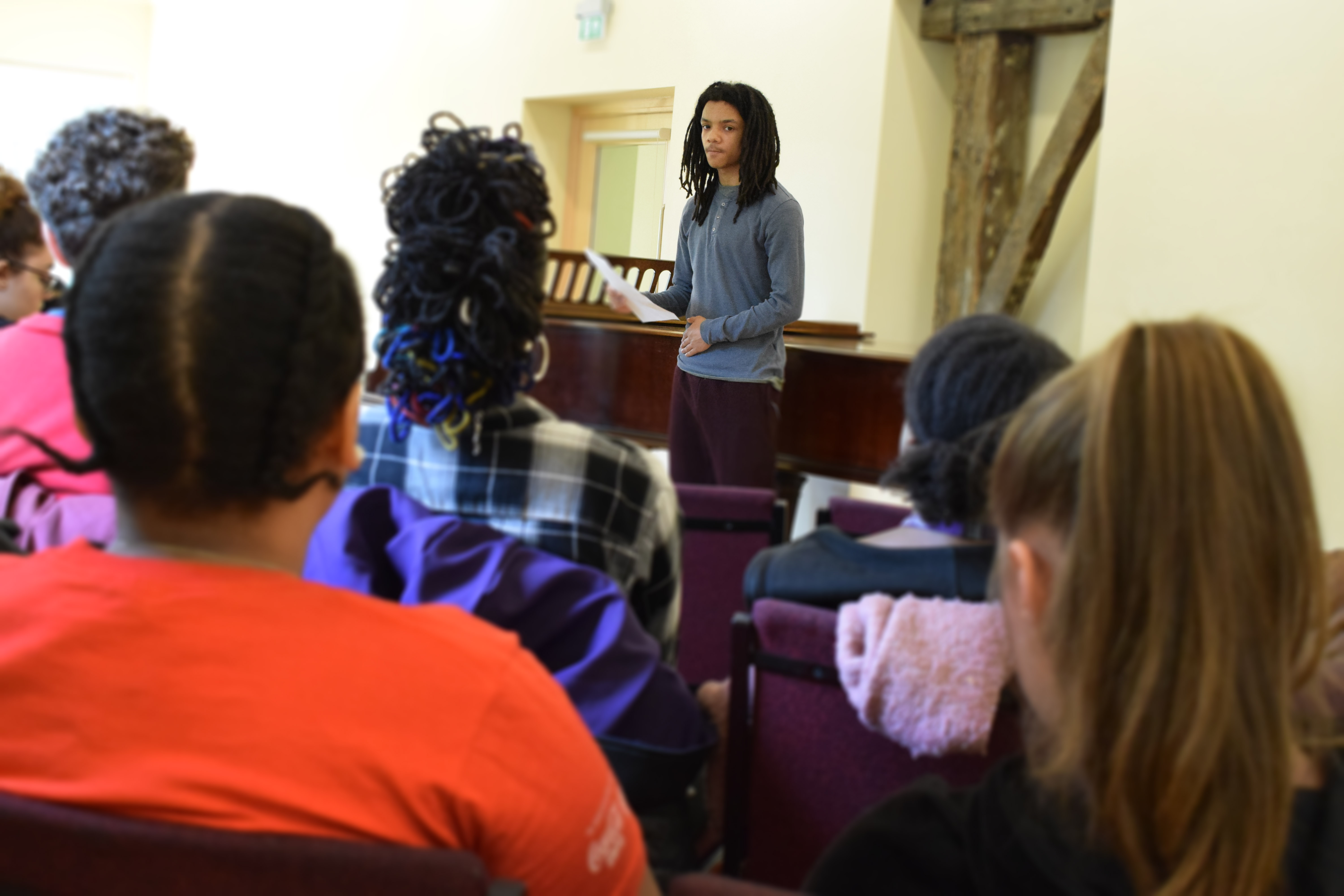 Student performing a poem to their peers