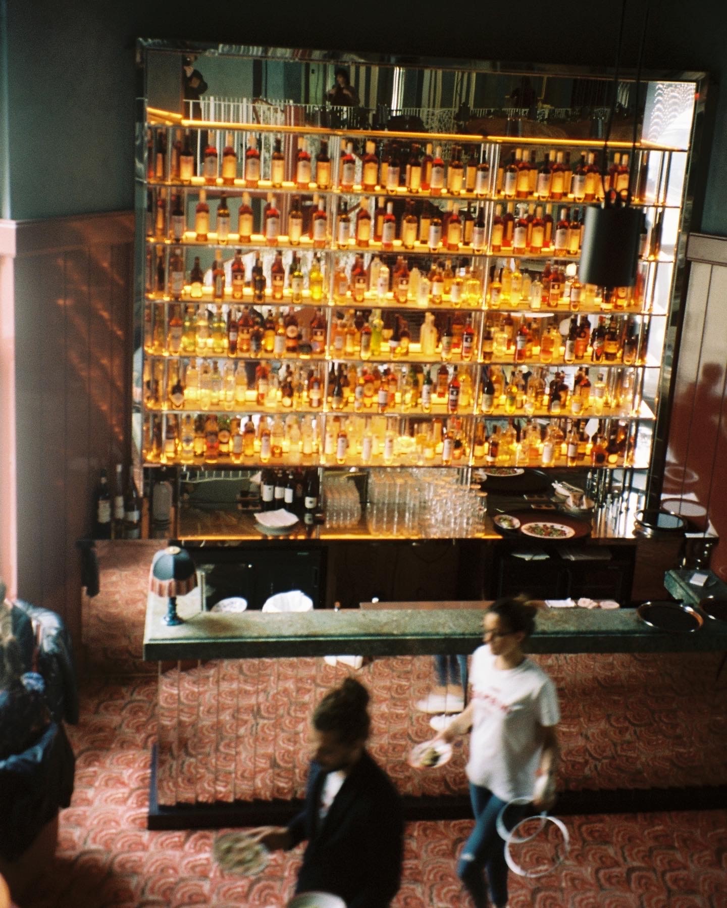 atmospheric scene of a bar with a lit wall of bottles