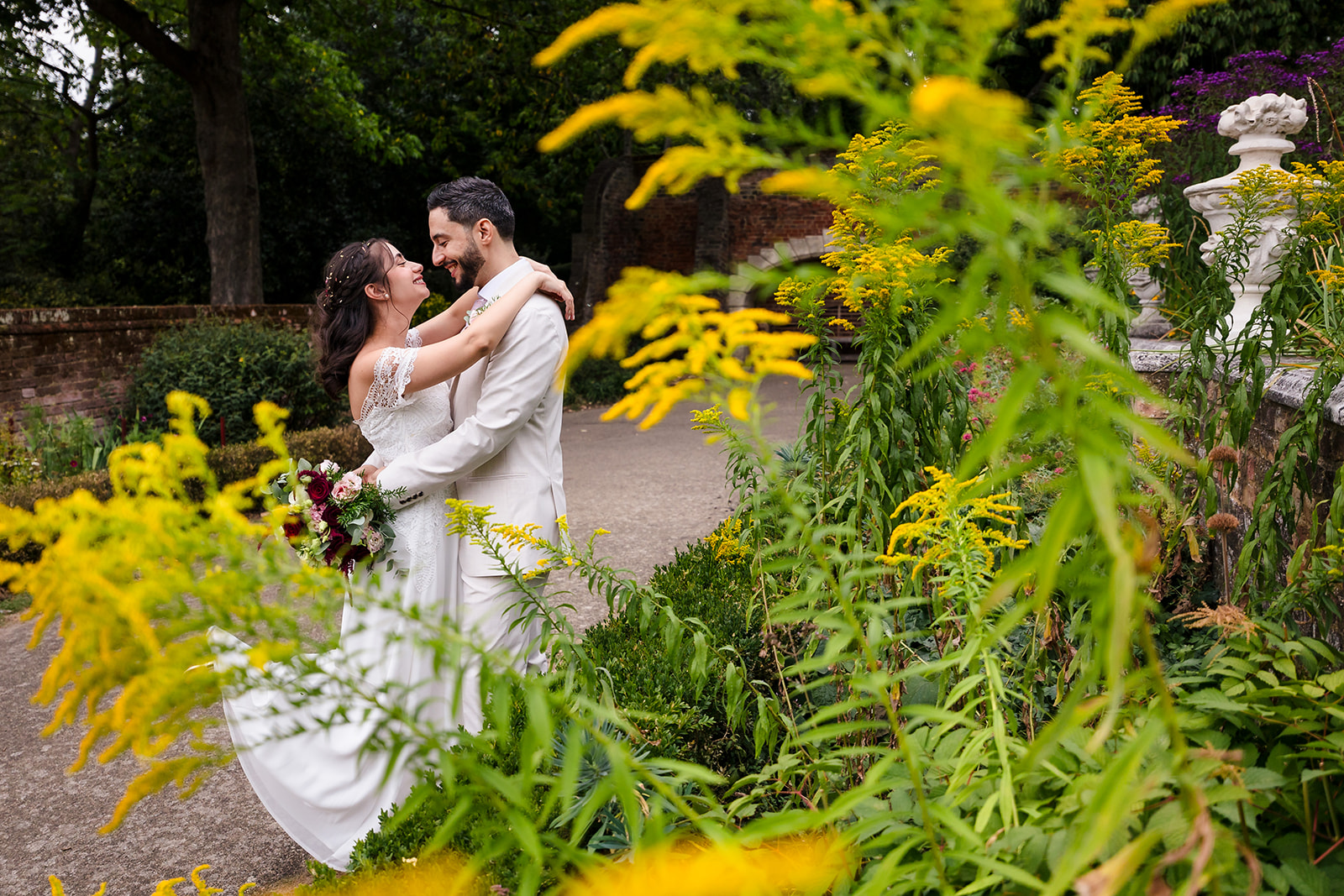 Bride and groom through the leaves at the end of the tea lawn
