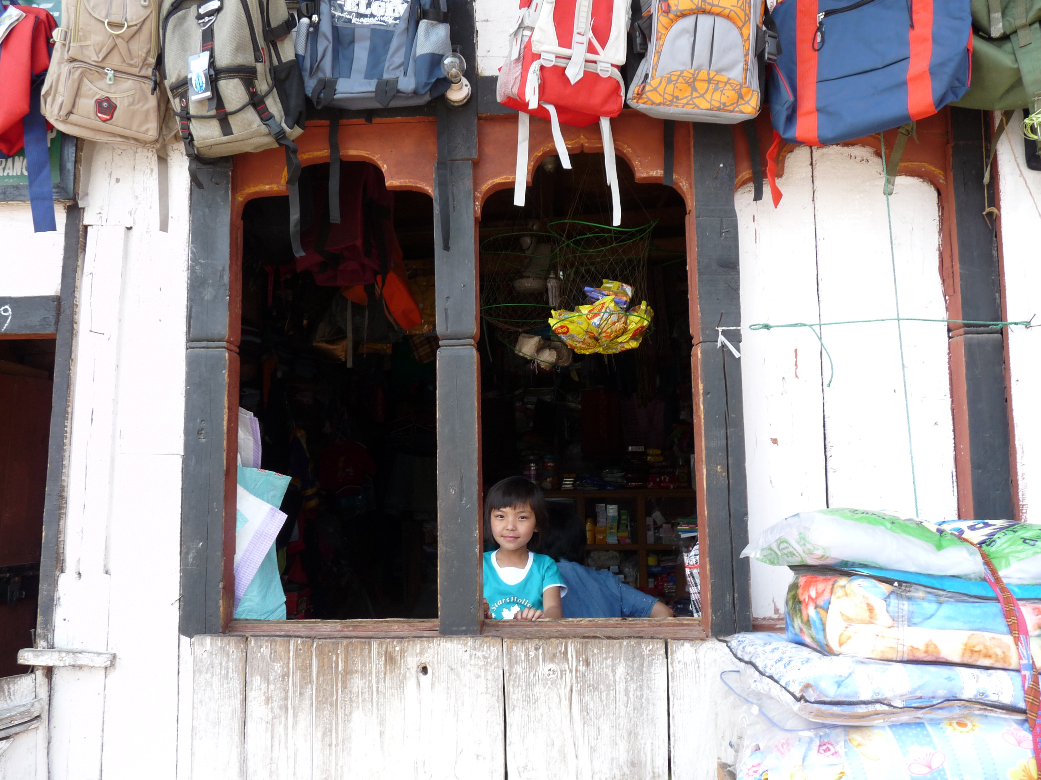 Photograph of a boy smiling through a window with colourful backpacks above him