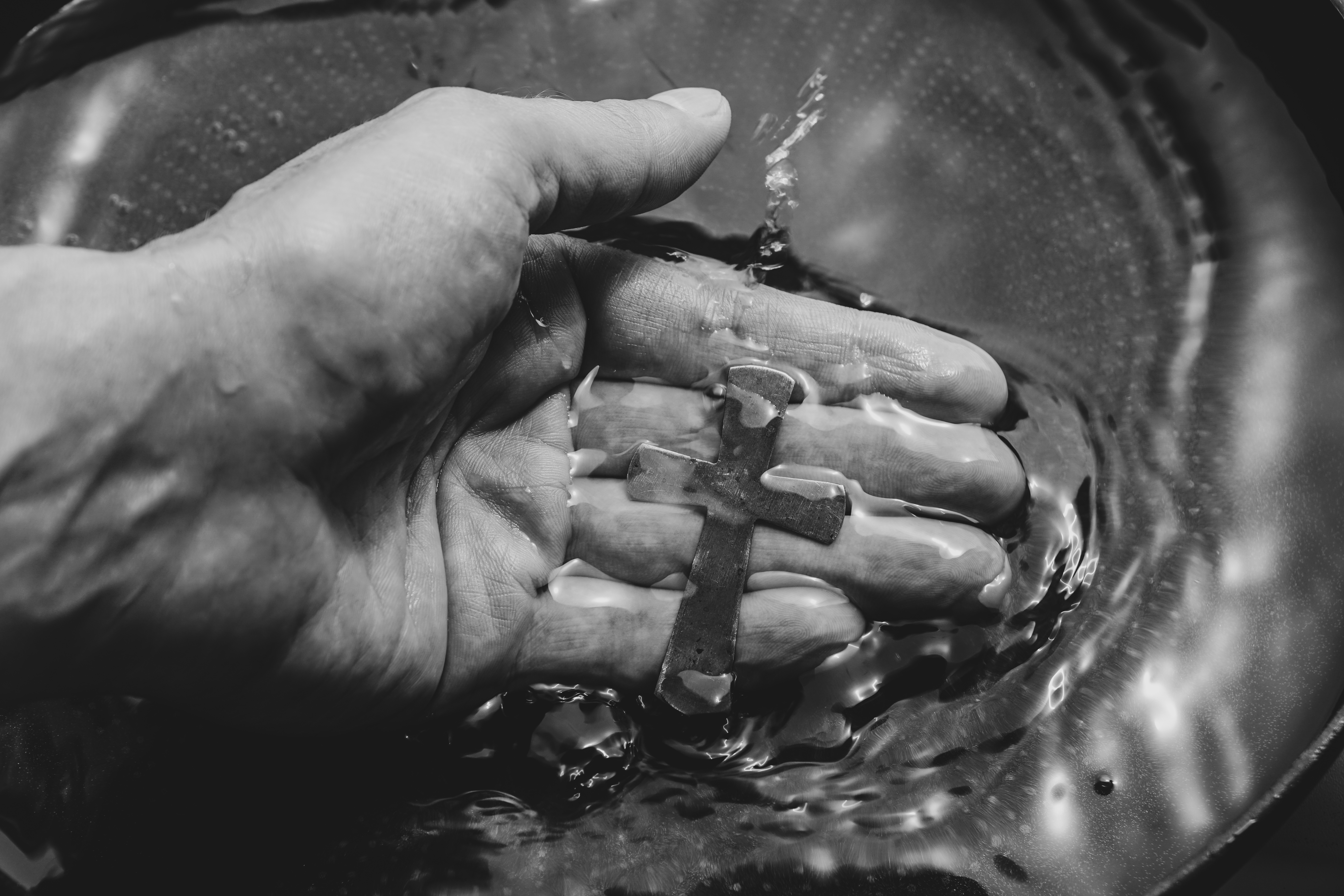 Black and white image of a hand holding a cross