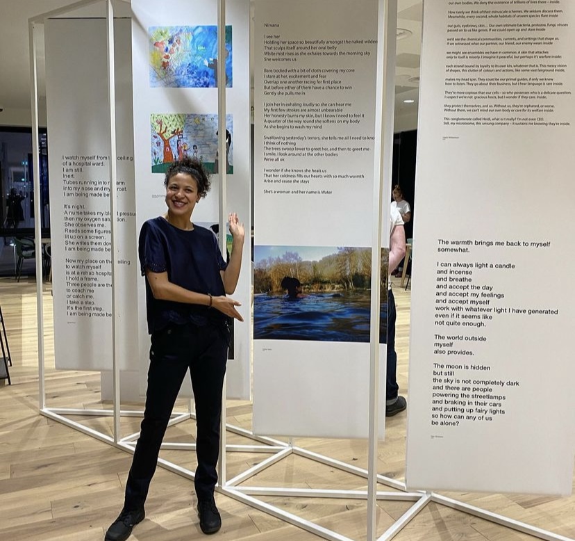 Woman smiling standing in front of artwork with text