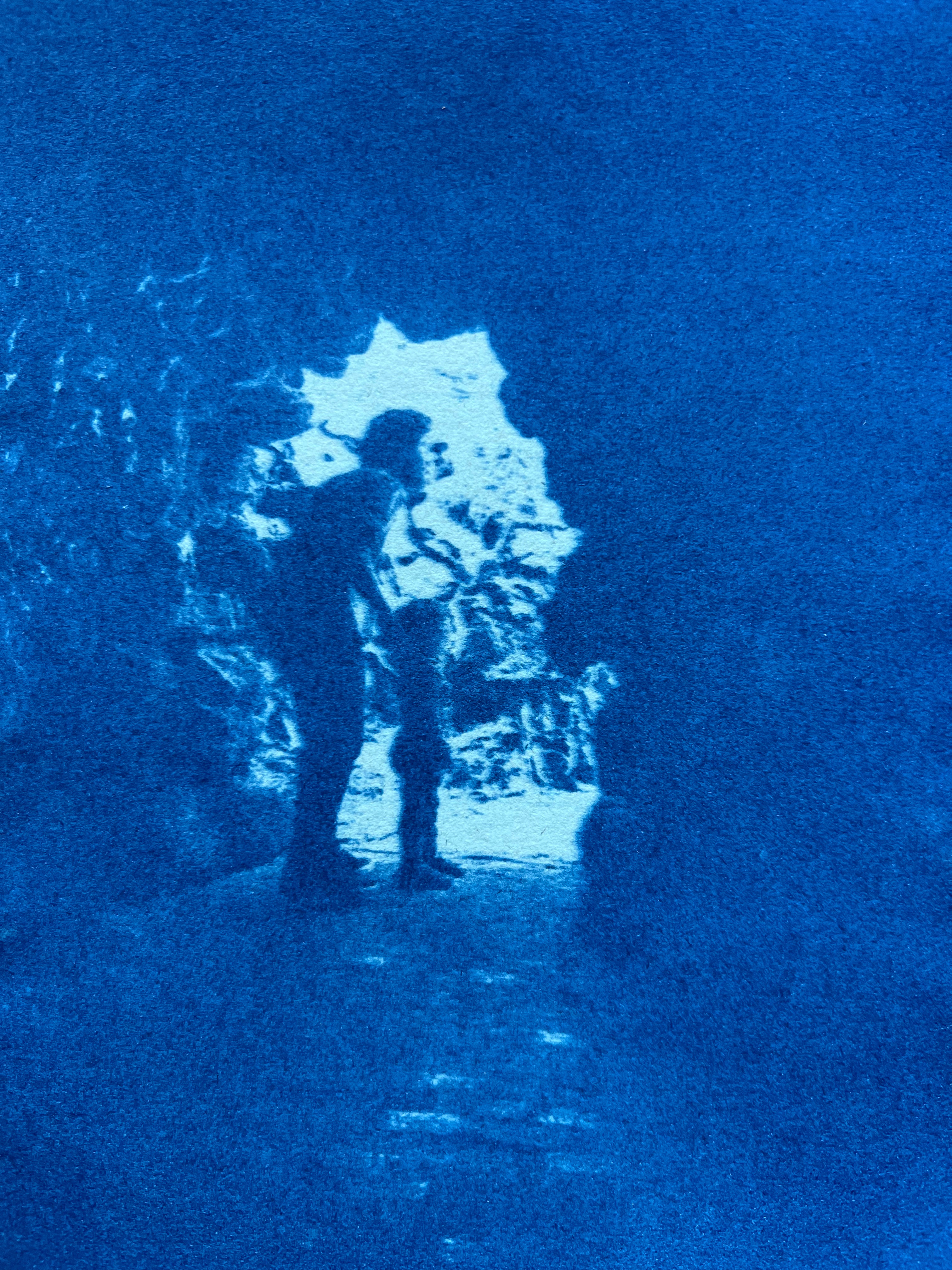 Cyanotype photo of an adult and child inside a cave