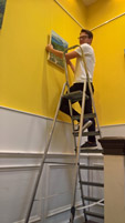 man on ladder hanging picture