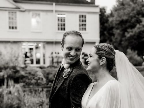 Black & white photo of P & J in front of the house credit Becky Wood Weddings